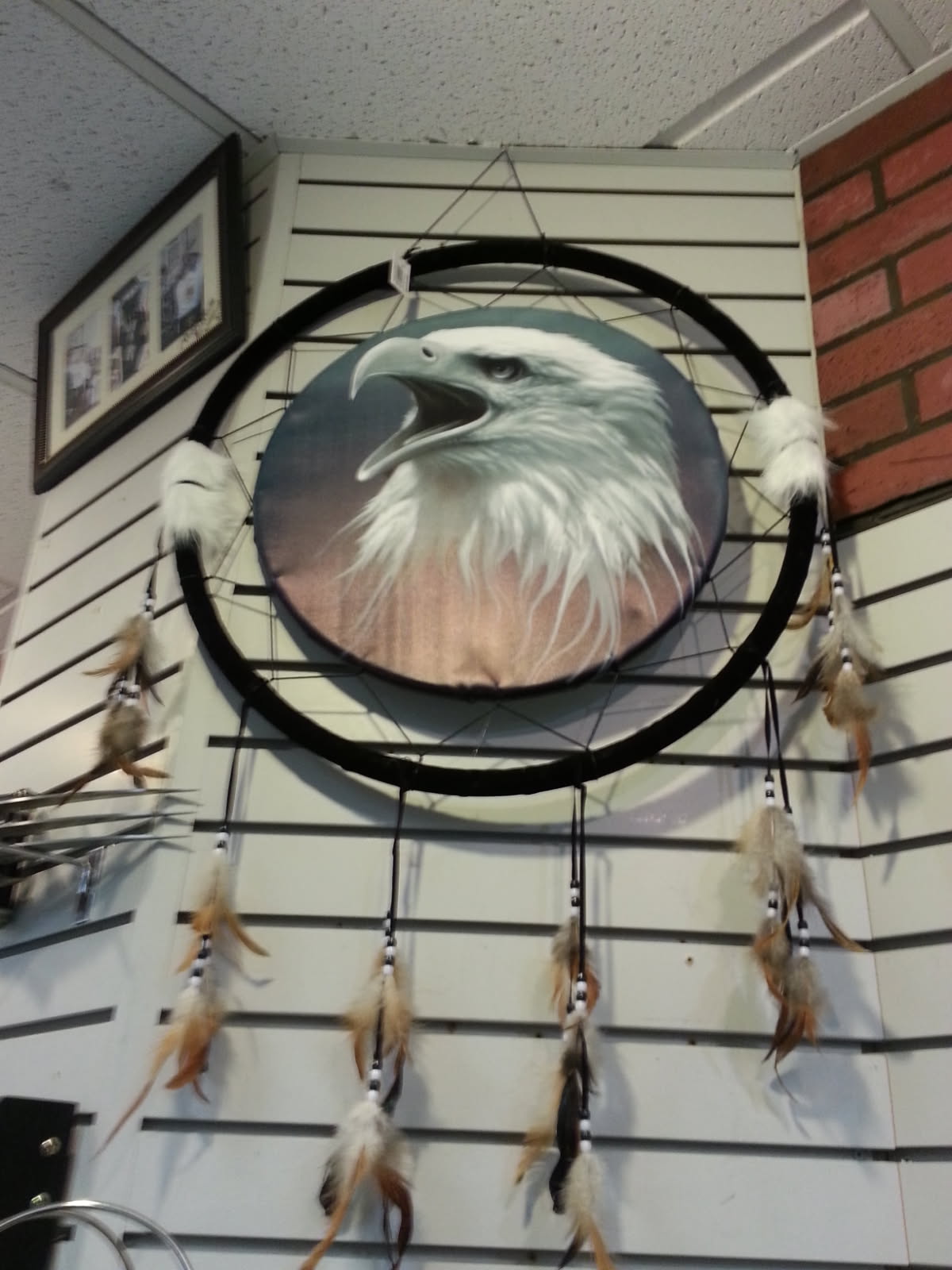 Large dream catcher with a screaming bald eagle painted on the hide, trimmed with feathers and fur