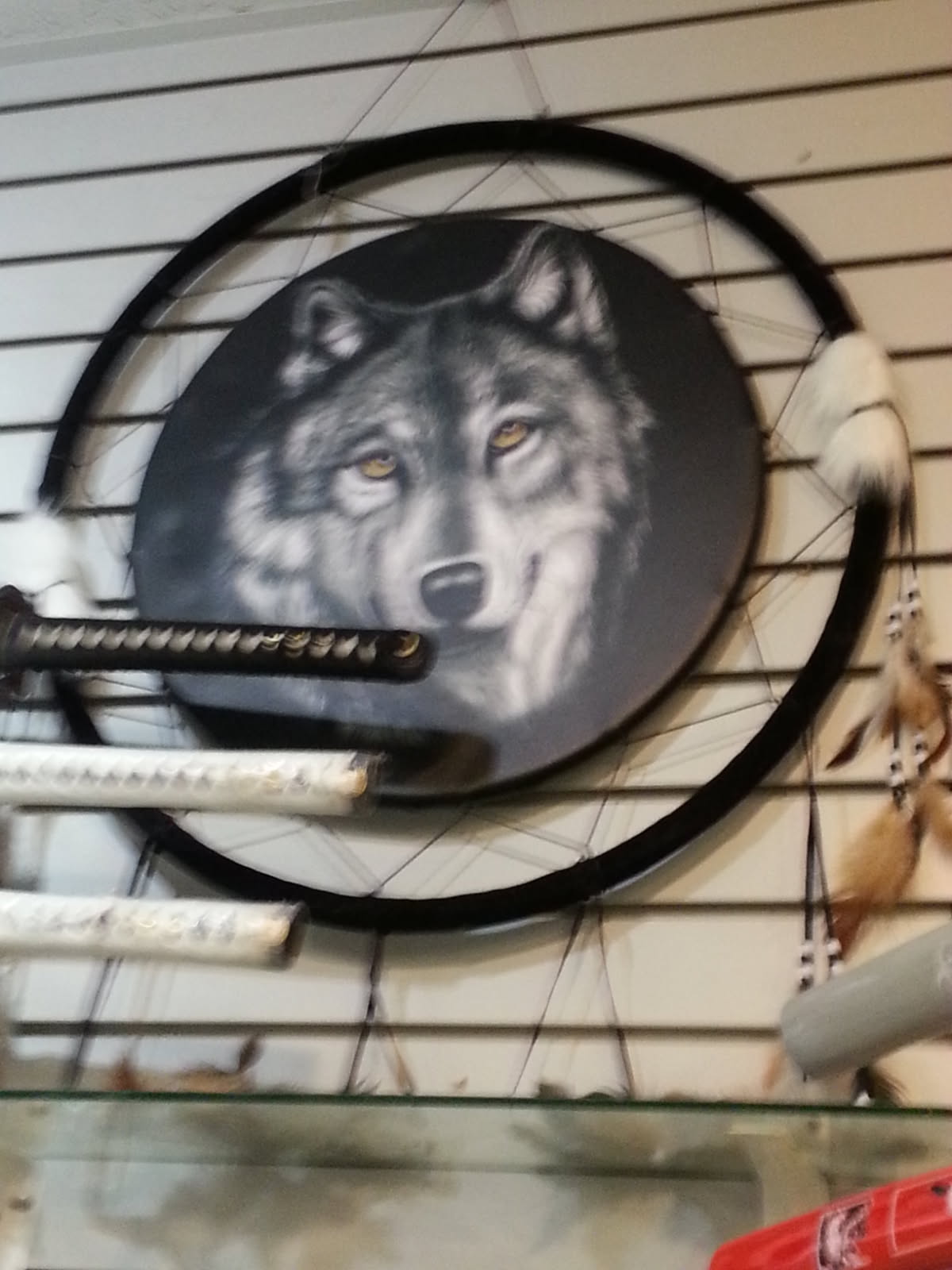 Dream catcher painted with a grey wolf's face, hung above a rack of katanas