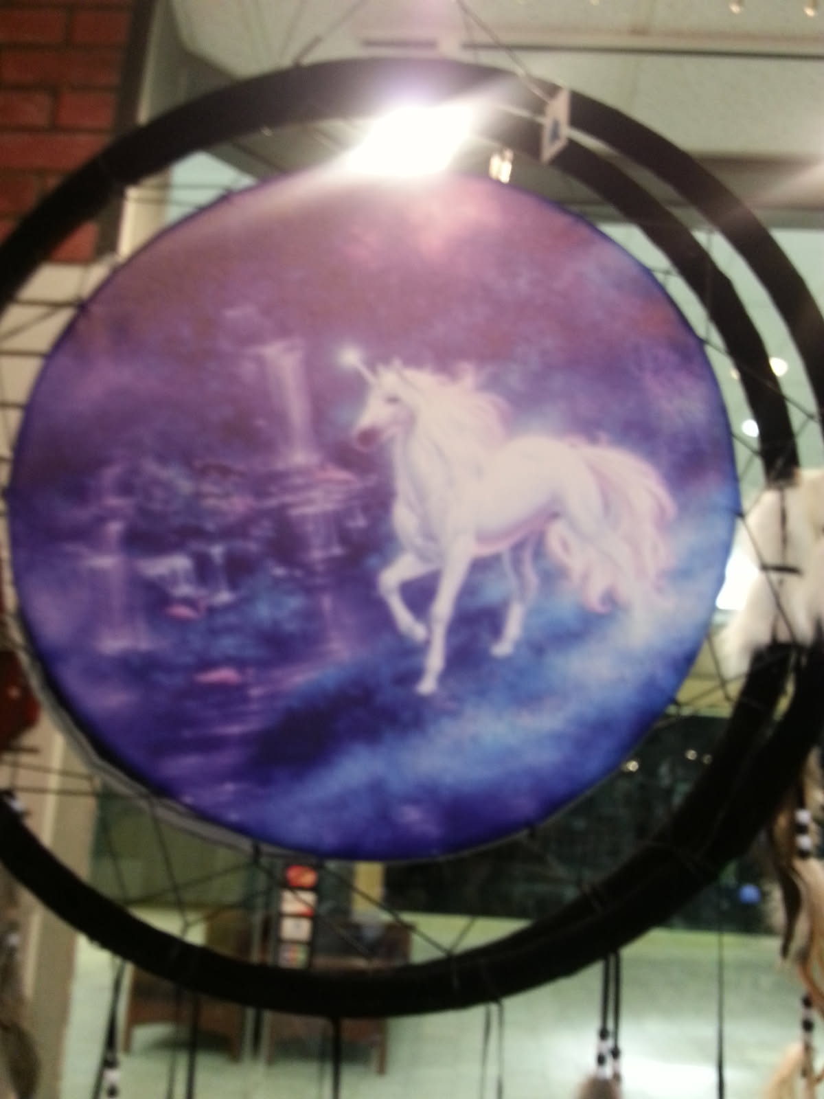 Dream catcher painted with a white unicorn on a purple and blue background