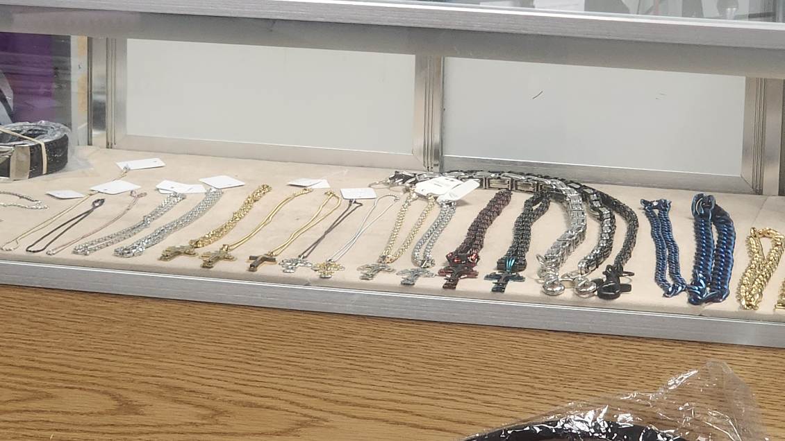 Counter display of cross-pendant necklaces and chain bracelets in gold, silver and blue finishes