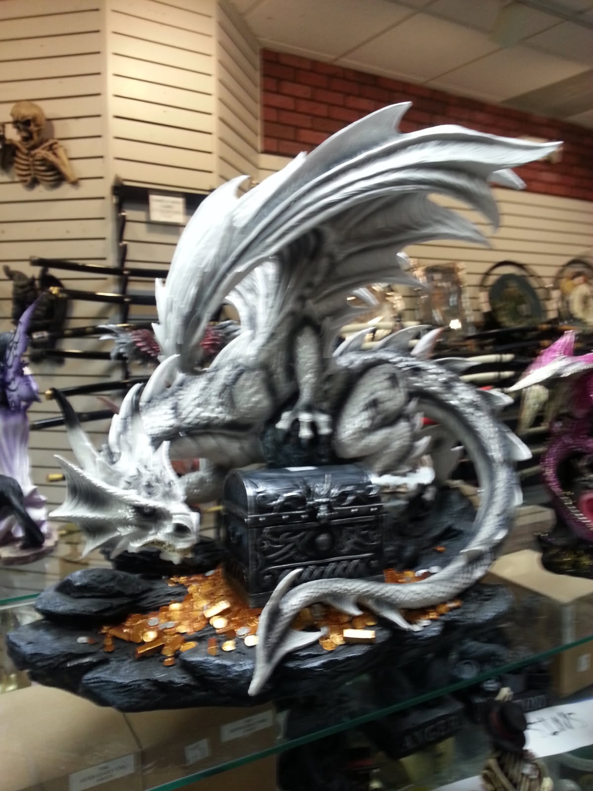White dragon figurine coiled around a black treasure chest spilling gold coins