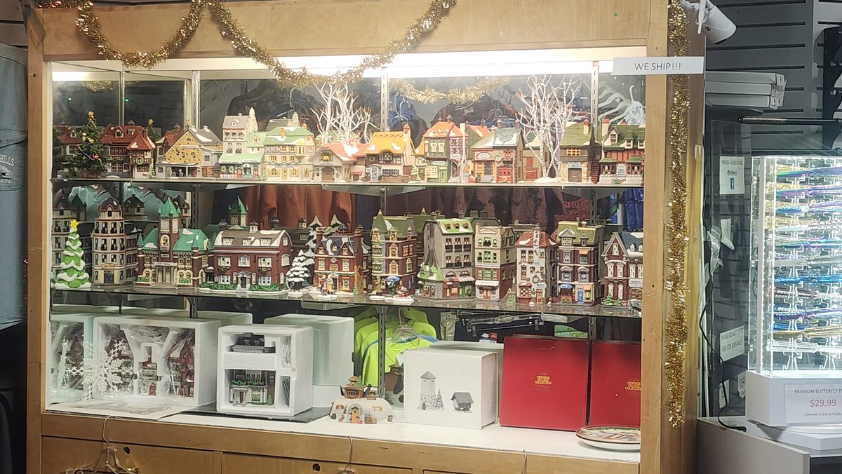 Lit glass case filled with collectible ceramic village houses and holiday d&eacute;cor