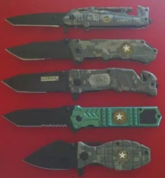 Five camouflage-finish tactical folding knives lined up in a display case