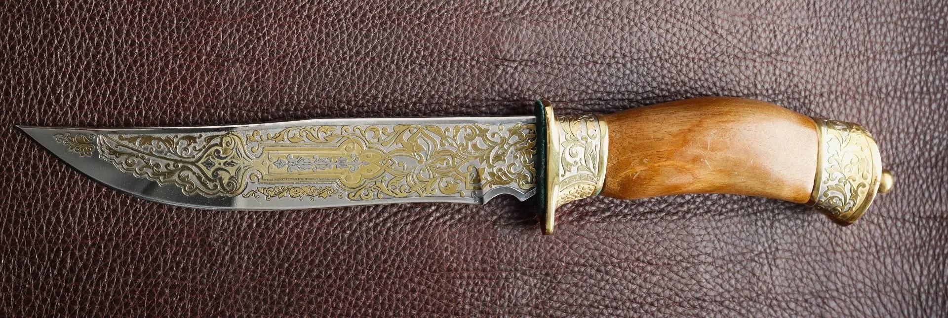 Engraved hunting knife with a polished wood and brass handle
